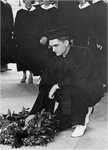 A Male Graduate Lays a Wreath on the Ground